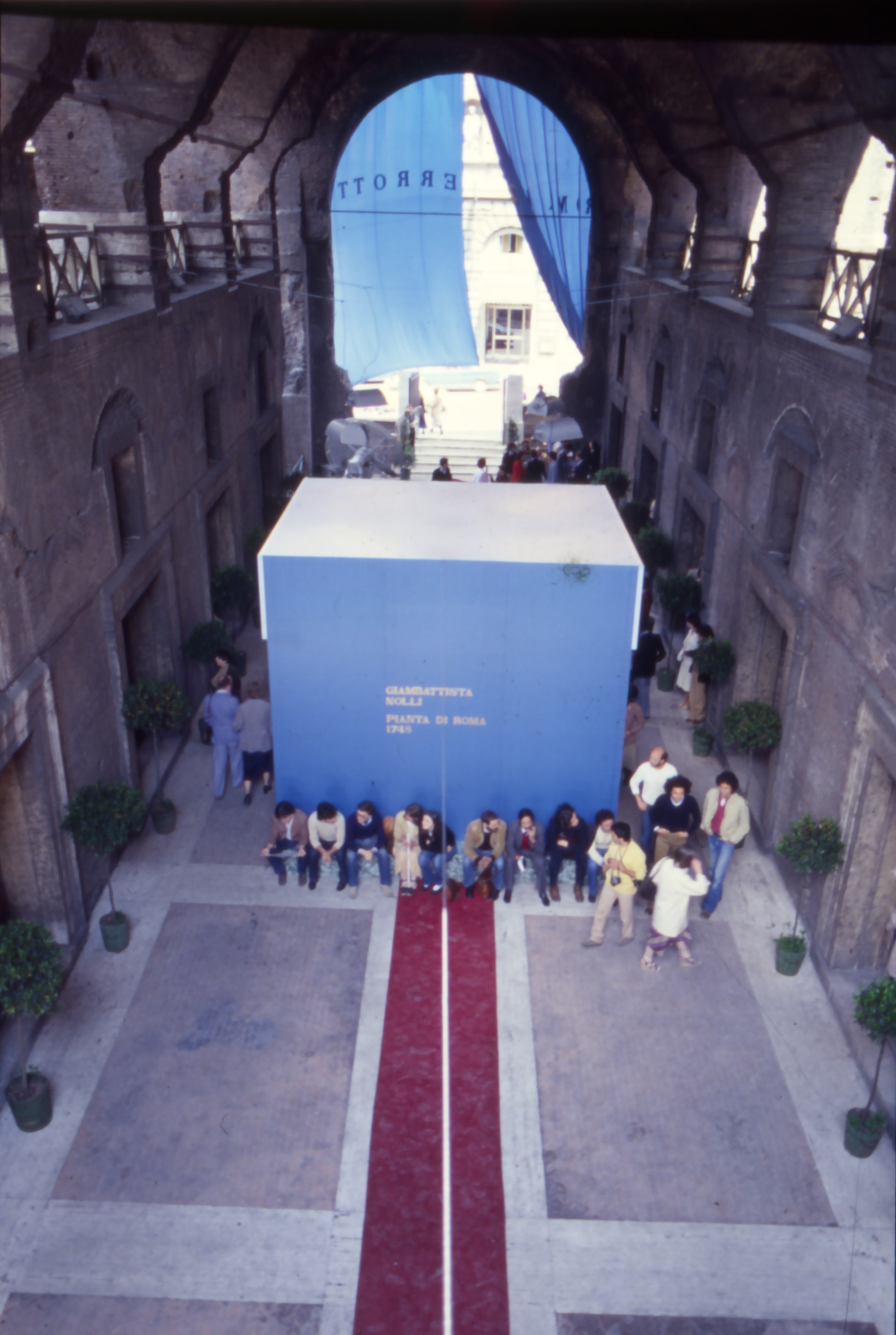 Entrance to the Mercati Traianei, the turquoise of the cube and the curtain contrasting with the red of the walkaway